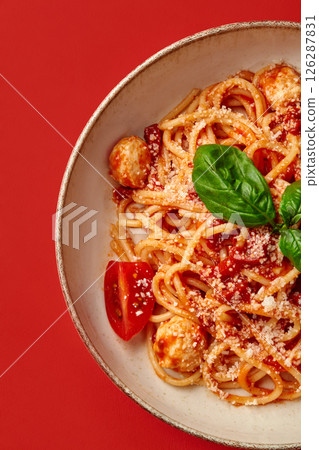 Delicious italian spaghetti with tomato sauce, meatballs and basil on red background Delicious italian spaghetti with tomato sauce, meatballs and basil on red background 126287831