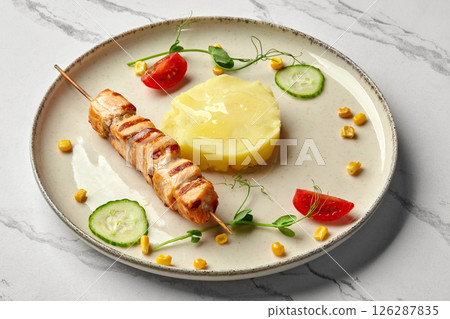 Grilled salmon skewer with mashed potatoes and vegetables on elegant plate 126287835