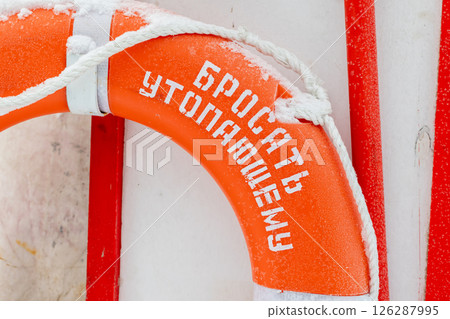 A vibrant orange lifebuoy covered in snow 126287995