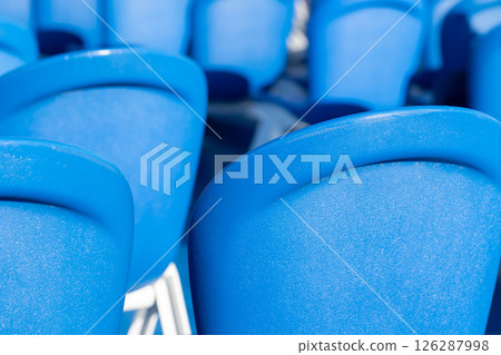 Brightly illuminated close-up of multiple blue plastic chairs Brightly illuminated close-up of multiple blue plastic chairs 126287998