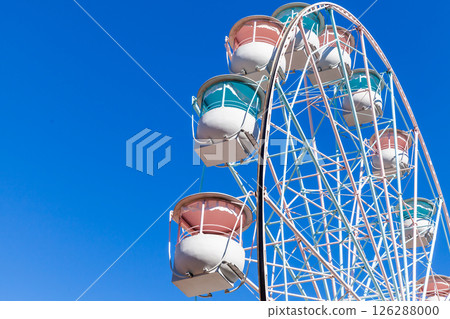 White Ferris wheel cabins with colorful details captured under blue sky White Ferris wheel cabins with colorful details captured under blue sky 126288000