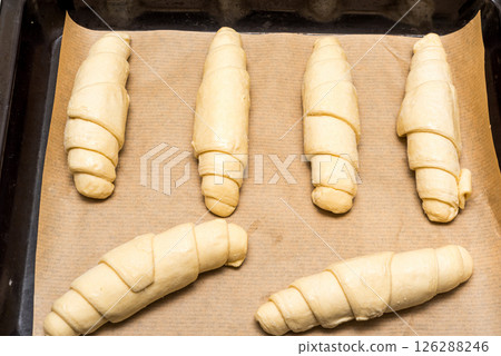 Croissant shaped dough on baking paper and baking tray, ready to bake croissants. 126288246