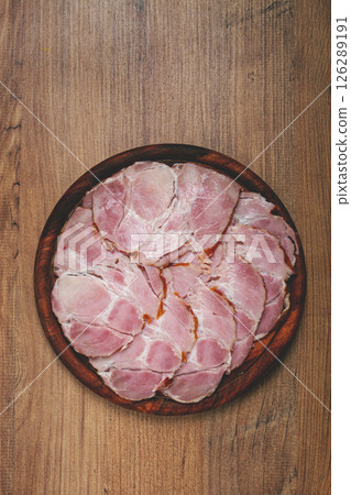sliced pork neck, boiled and smoked, smoked pork neck, sliced, on a wooden chopping board, close-up, 126289191