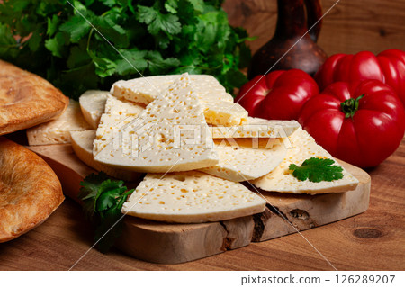 Georgian sliced cheese,on a wooden chopping board, with tomatoes with herbs and lavash, rustic style, Georgian cuisine, no people 126289207