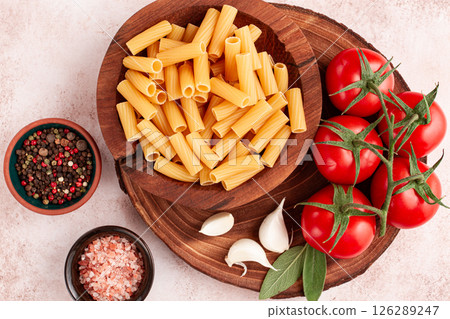Pasta ingredients spread out, on a wooden surface, with tomatoes and spices, ready to cook, there are no people 126289247