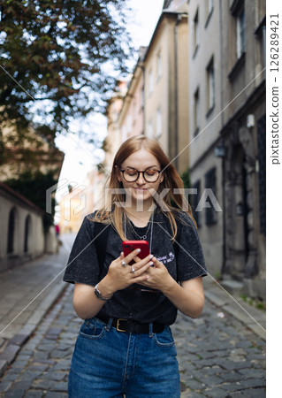 Young woman browsing smartphone while walking outside Young woman browsing smartphone while walking outside 126289421