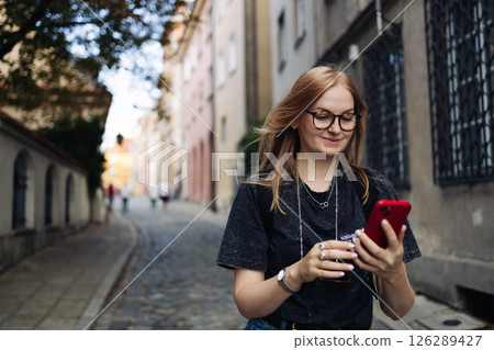 Young woman browsing smartphone while walking outside Young woman browsing smartphone while walking outside 126289427