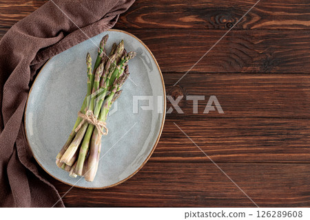 Asparagus tied bundle on brown plate on rustic table. Top view Asparagus tied bundle on brown plate on rustic table. Top view 126289608