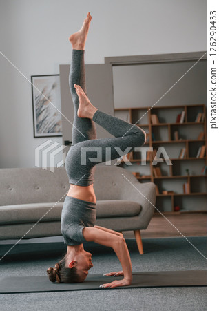 Making headstand. Young woman in yoga clothes doing fitness indoors 126290433
