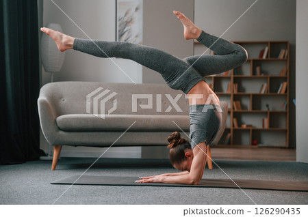 Making handstand. Young woman in yoga clothes doing fitness indoors 126290435