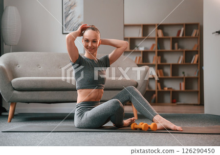 Relaxed, on the mat. Young woman in yoga clothes doing fitness indoors 126290450