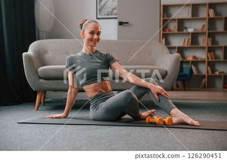 Relaxed, on the mat. Young woman in yoga clothes doing fitness indoors 126290451