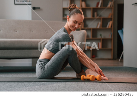 In apartment. Young woman in yoga clothes doing fitness indoors In apartment. Young woman in yoga clothes doing fitness indoors 126290453
