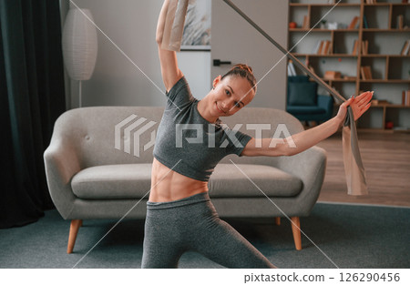 Exercises by using piece of cloth. Young woman doing fitness indoors 126290456