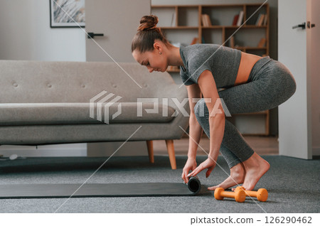 Rolling off the mat. Young woman in yoga clothes doing fitness indoors Rolling off the mat. Young woman in yoga clothes doing fitness indoors 126290462