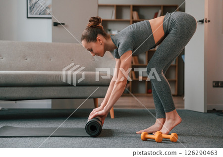 Rolling off the mat. Young woman in yoga clothes doing fitness indoors Rolling off the mat. Young woman in yoga clothes doing fitness indoors 126290463