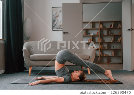 Spine exercises. Young woman in yoga clothes doing fitness indoors Spine exercises. Young woman in yoga clothes doing fitness indoors 126290470