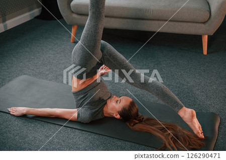 Asana with legs up. Young woman in yoga clothes doing fitness indoors Asana with legs up. Young woman in yoga clothes doing fitness indoors 126290471