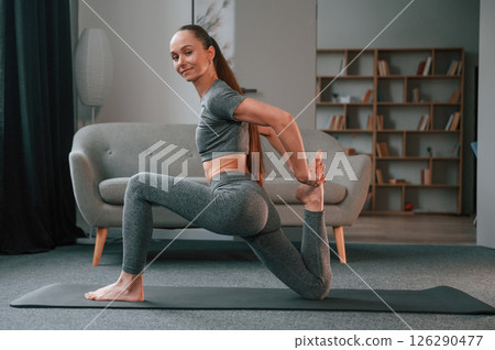 Side view. Young woman in yoga clothes doing fitness indoors Side view. Young woman in yoga clothes doing fitness indoors 126290477