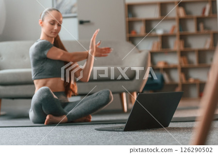 Using laptop. Young woman in yoga clothes doing fitness indoors Using laptop. Young woman in yoga clothes doing fitness indoors 126290502