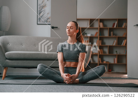 In apartment. Young woman in yoga clothes doing fitness indoors 126290522