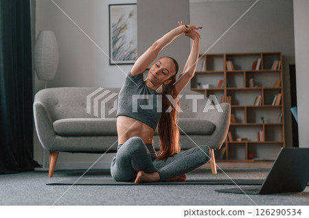 Warm up exercises. Young woman in yoga clothes doing fitness indoors 126290534
