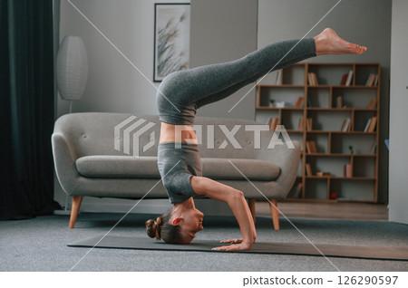 Making headstand. Young woman in yoga clothes doing fitness indoors 126290597