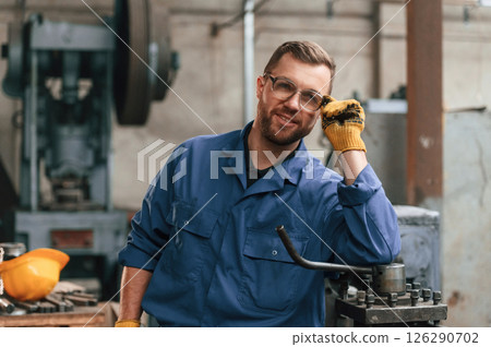 Front view. Factory worker in blue uniform is indoors 126290702