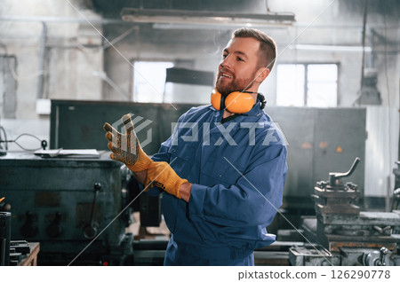 Working by using digital tablet. Man at the factory that is in blue uniform is indoors Working by using digital tablet. Man at the factory that is in blue uniform is indoors 126290778