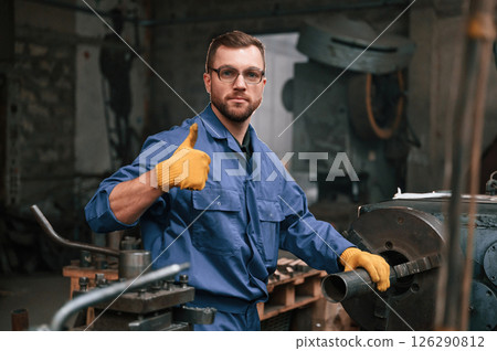 Job is done. Showing thumb up. Factory worker in blue uniform is indoors Job is done. Showing thumb up. Factory worker in blue uniform is indoors 126290812