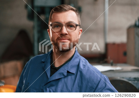 Portrait of factory worker that is in blue uniform indoors Portrait of factory worker that is in blue uniform indoors 126290820
