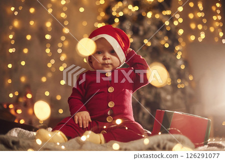 In Santa hat. Cute little baby is at home. New year decorations. Conception of holidays 126291077