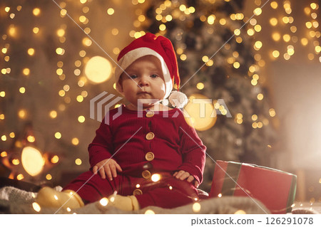 In Santa hat. Cute little baby is at home. New year decorations. Conception of holidays In Santa hat. Cute little baby is at home. New year decorations. Conception of holidays 126291078