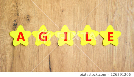 Agile symbol. Concept word Agile on beautiful yellow paper stars. Beautiful wooden table wooden background. Business flexible and agile concept. Copy space. 126291206