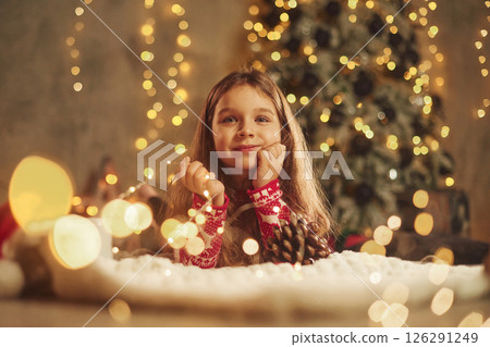 Cute little girl is lying down on the floor at home, celebrating New Year Cute little girl is lying down on the floor at home, celebrating New Year 126291249