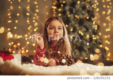Cute little girl is lying down on the floor at home, celebrating New Year Cute little girl is lying down on the floor at home, celebrating New Year 126291252