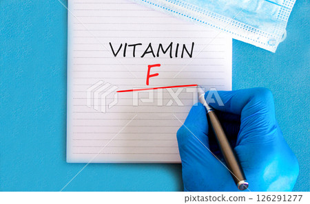 Vitamin F symbol. Concept words Vitamin F on beautiful white note. Doctor's hand in blue medical glove. Medical mask. Beautiful blue background. Medical healthy lifestyle Vitamin F concept. Vitamin F symbol. Concept words Vitamin F on beautiful white note. Doctor's hand in blue medical glove. Medical mask. Beautiful blue background. Medical healthy lifestyle Vitamin F concept. 126291277