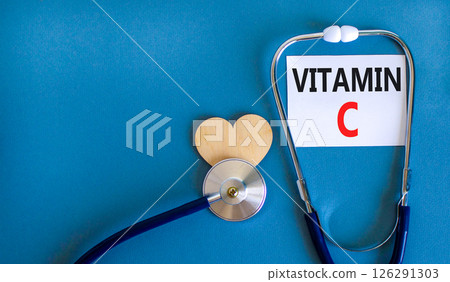 Vitamin C symbol. Concept words Vitamin C on beautiful white card. Wooden heart and stethoscope. Beautiful blue background. Medical healthy lifestyle Vitamin C concept. 126291303