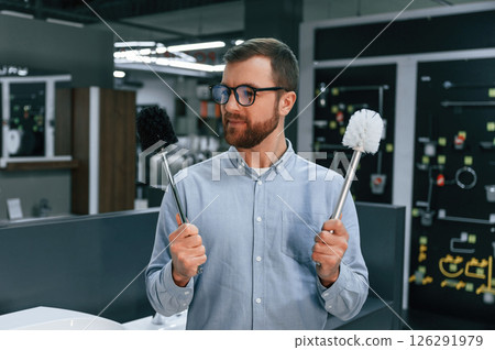 Holding two toilet brushes. Man chooses a products in a sanitary ware store 126291979