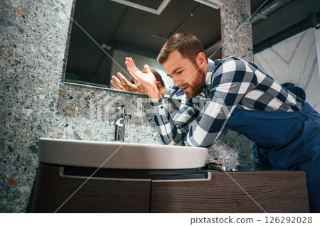 Can't fix the crane. Plumber in blue uniform is at work in the bathroom 126292028