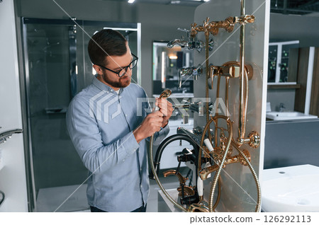Selects a shower faucet. Man chooses a products in a sanitary ware store 126292113