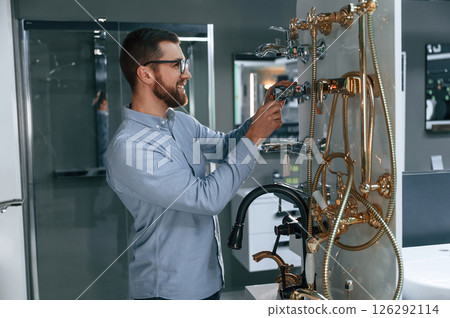 Selects a shower faucet. Man chooses a products in a sanitary ware store 126292114