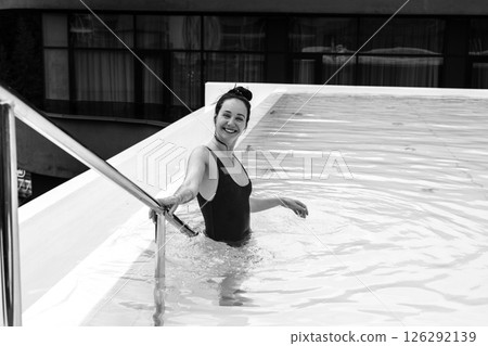 A radiant woman smiles broadly, enjoying a serene moment in a cool, refreshing pool. A girl is smiling happily while relaxing in the pool. Summer fun. 126292139