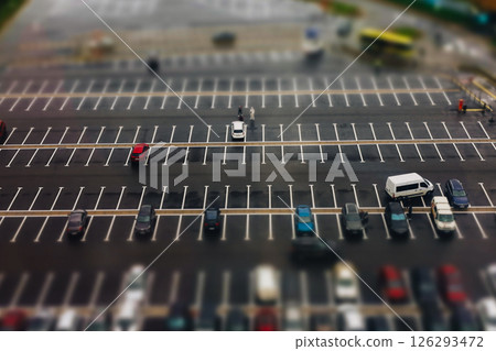 A top-down shot reveals a well-organized huge parking lot filled with various cars. An aerial view showcases various vehicles on urban city parking. 126293472