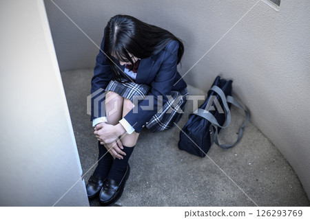 High school girl crouching on the landing of the stairs: Bullying, school refusal, anxiety about the future 126293769