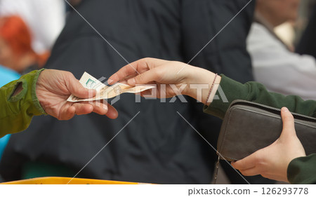 Two Hands Exchanging Cash in a Public Outdoor Market 126293778