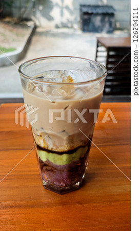 Layered Avocado Mocha Drink with Ube and Sweet Toppings in a Glass on a Wooden Table in an Outdoor Setting Layered Avocado Mocha Drink with Ube and Sweet Toppings in a Glass on a Wooden Table in an Outdoor Setting 126294111