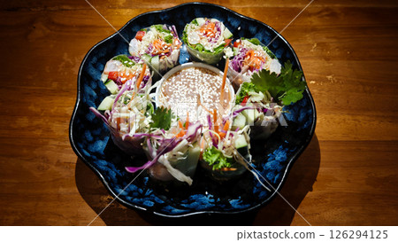 Colorful Shrimp Vietnamese Fresh Spring Rolls with Hoisin Sauce Served in a Blue Plate on Wooden Table Colorful Shrimp Vietnamese Fresh Spring Rolls with Hoisin Sauce Served in a Blue Plate on Wooden Table 126294125