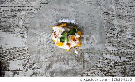 Elegant Presentation of Mango Sticky Rice with Coconut Cream on a Glass Plate with Mint Leaves Garnish, Captured in a Bright Rustic Setting 126294130
