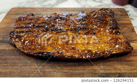 Grilled Barbeque Meat on a Wooden Cutting Board with Caramelized Glaze 126294151
